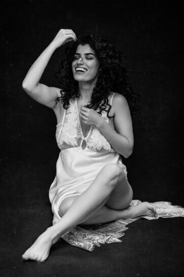 Woman seated in a silk dress against a dark studio background