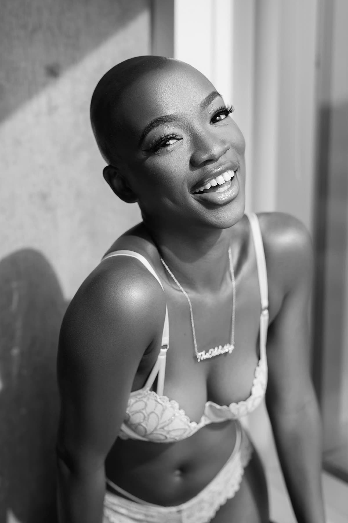 Smiling woman in white lingerie photographed in soft black and white light