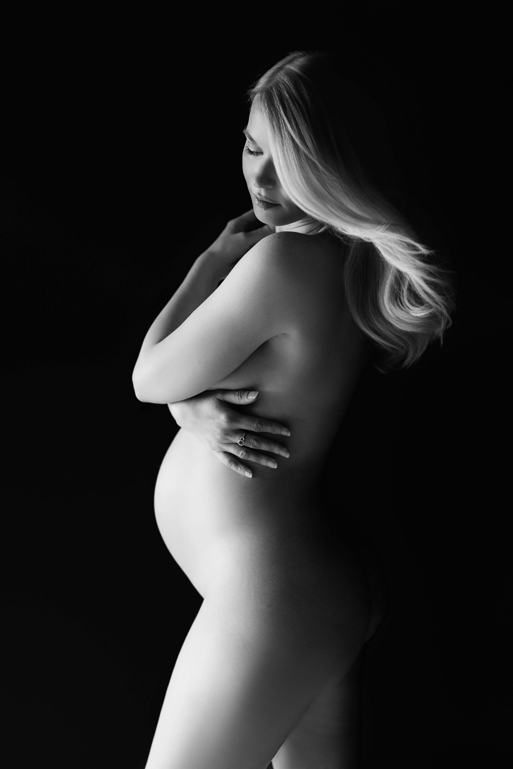 Pregnant woman in profile with long hair and soft black-and-white studio lighting